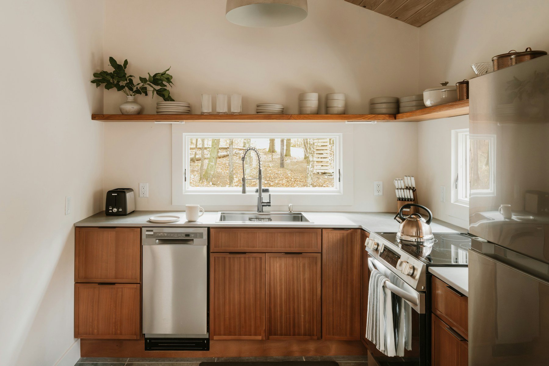 Timber kitchen cabinetry, open shelves and a bright window above the sink.